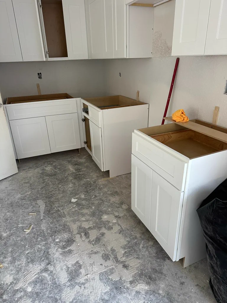 White shaker kitchen cabinets being installed on an active job site