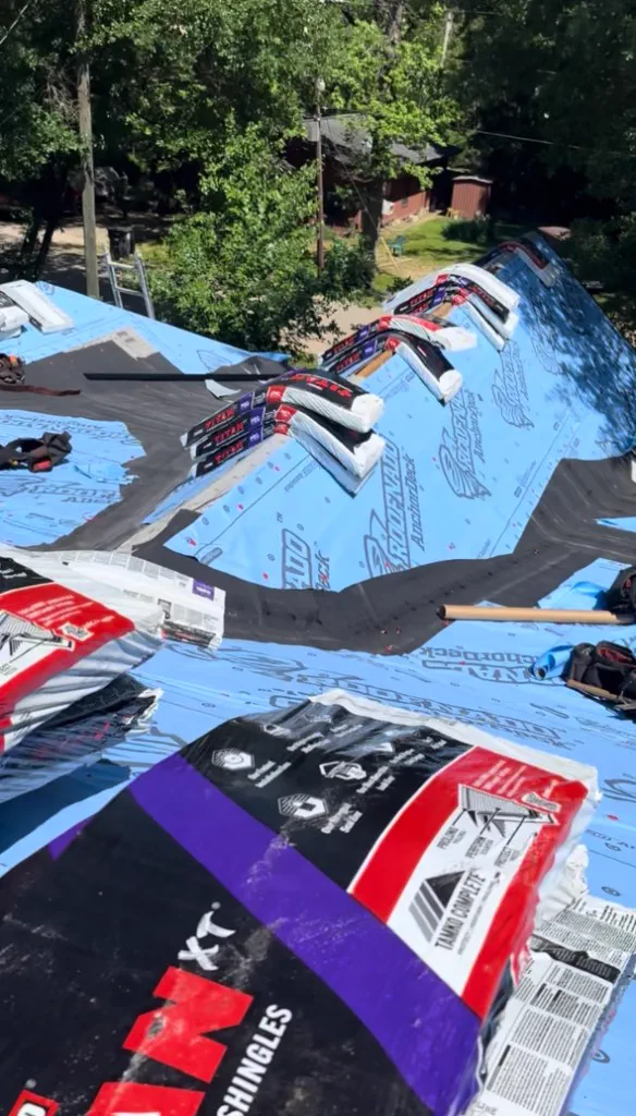Roof deck with blue synthetic underlayment and shingle bundles ready to install